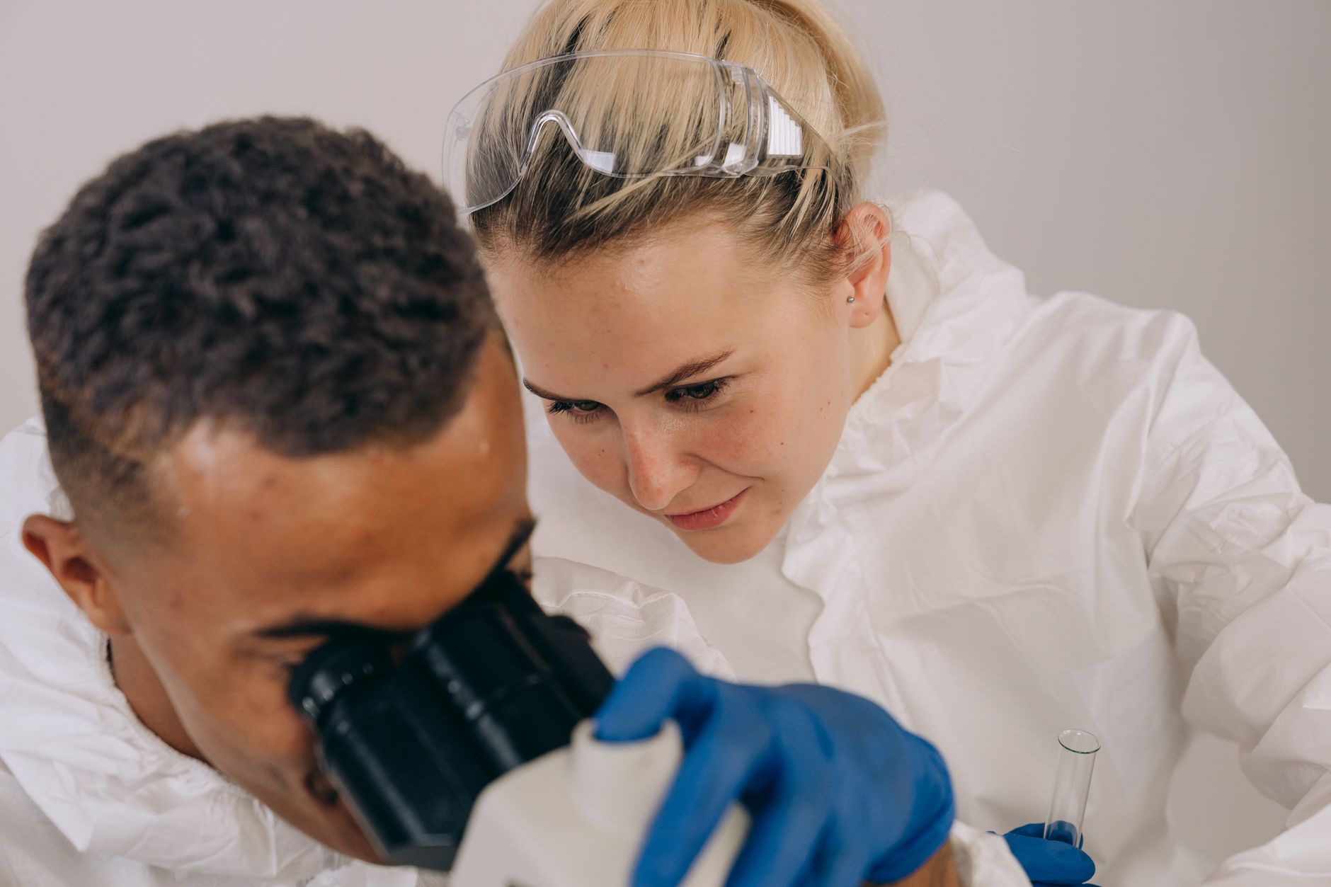 Dos técnicos de laboratorio trabajando con microscopio en bata blanca